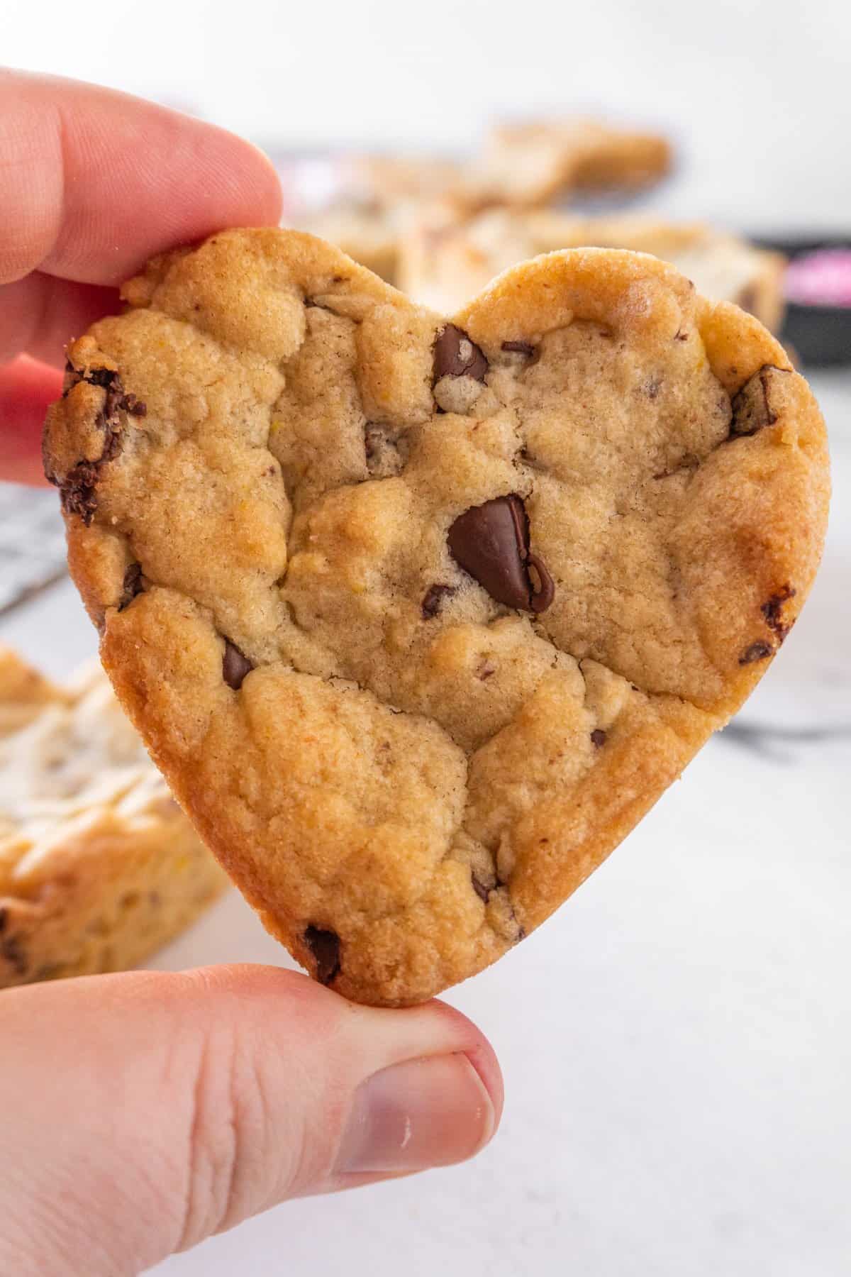 holding heart shaped chocolate chip cookie