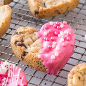 heart shaped chocolate chip half dipped in pink coating on cooling rack- featured image.