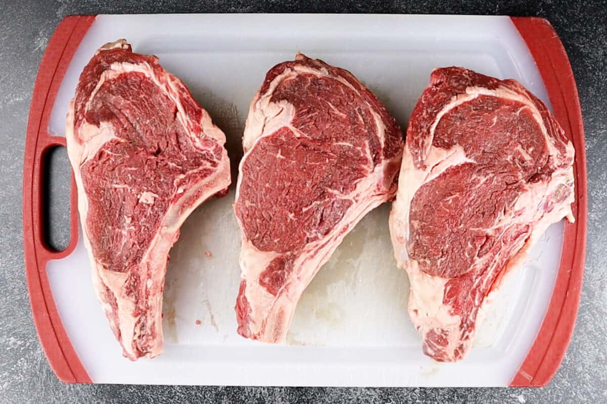 raw ribeye steaks on cutting board
