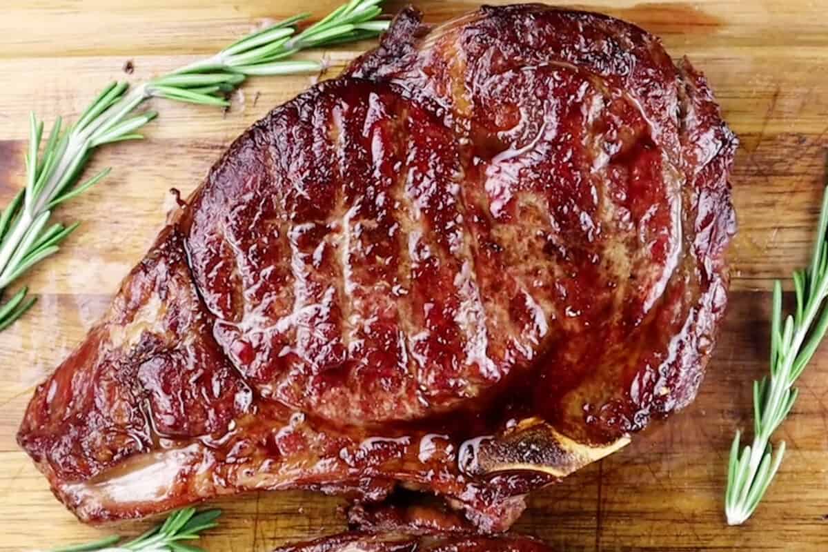 smoked ribeye on cutting board with rosemary surrounding it