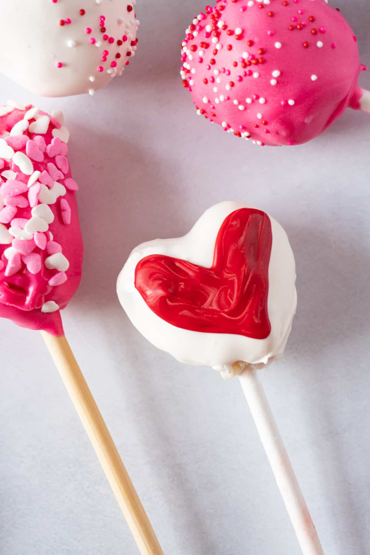 white heart cake pop with red heart painted on top