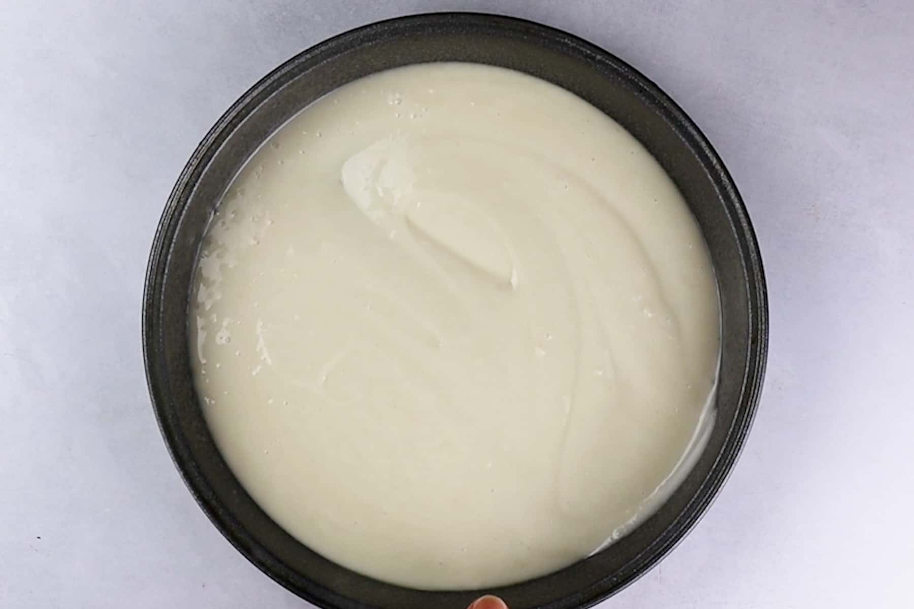 white cake batter in the cake pan before baking.