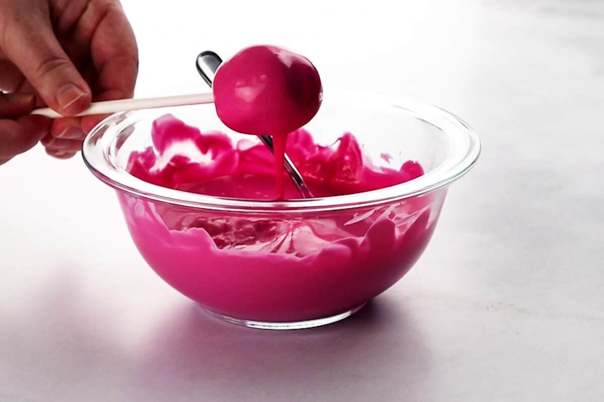 tapping dipped cake pop onto side of bowl