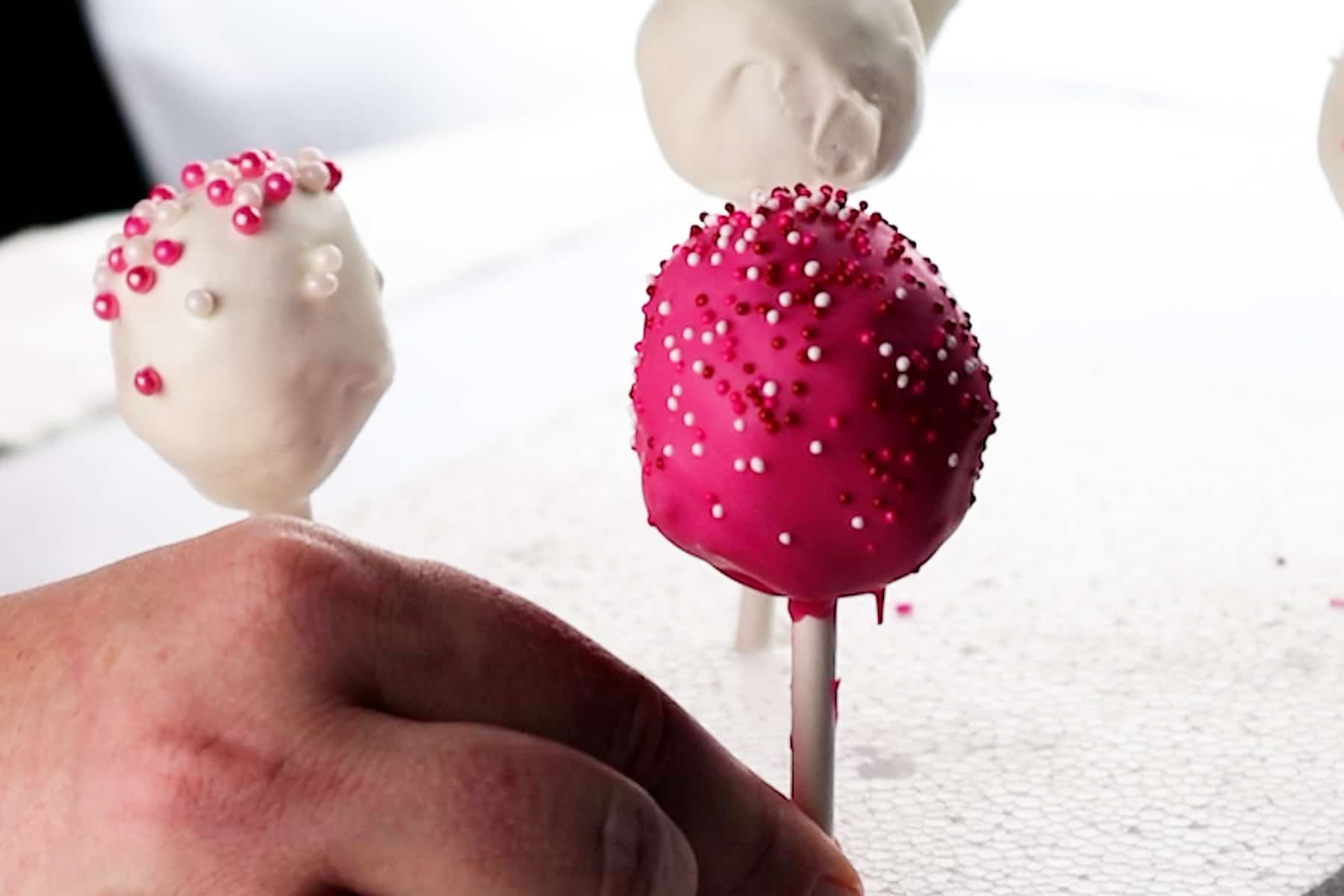 placing dipped cake pop into Styrofoam to stand up.