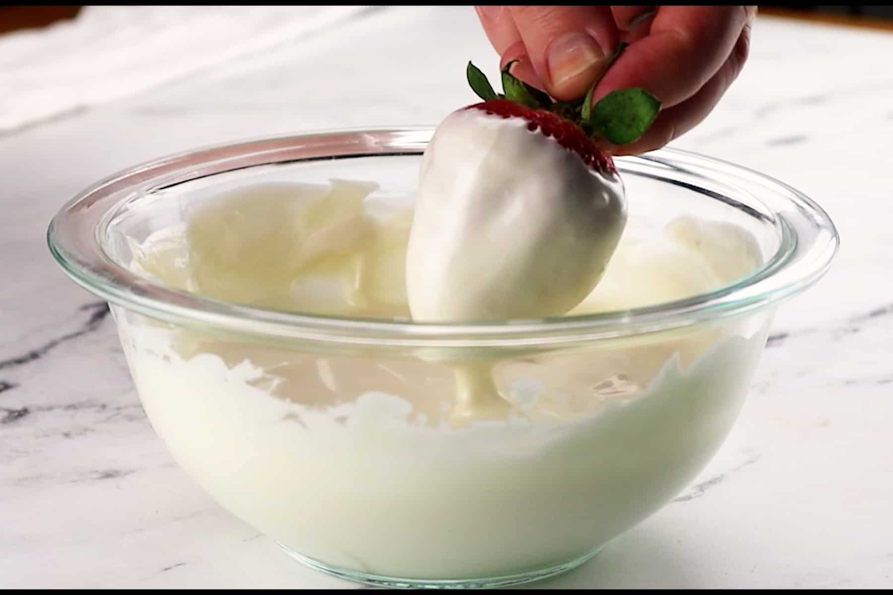 dipping strawberry in white candy melts.