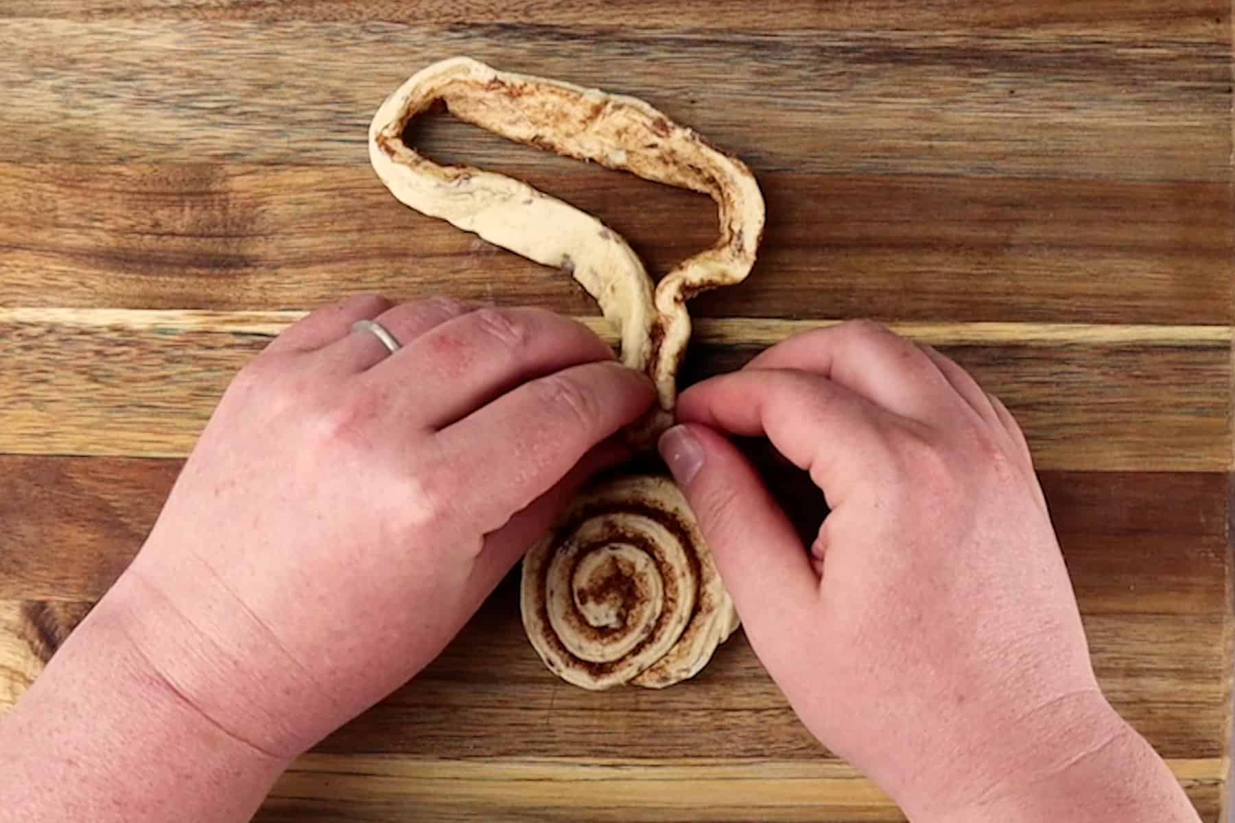 pressign dough to top of cinnamon roll
