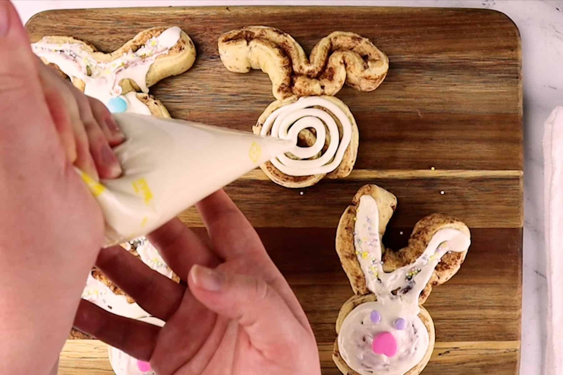 adding frosting to bunny cinnamon rolls