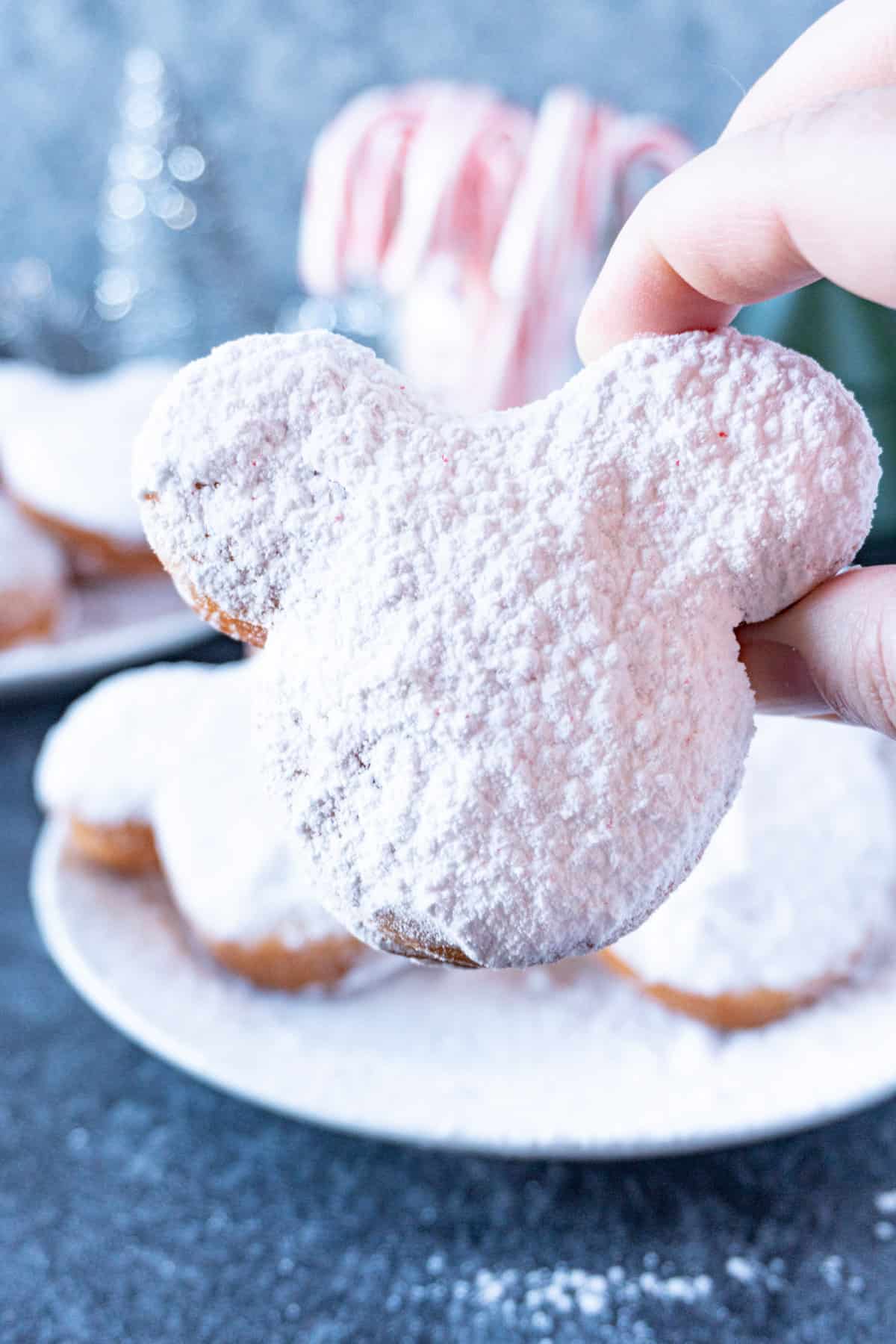 holding a candy cane beignet in hand