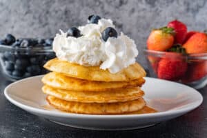 air fryer pancakes stacked with whipped cream on top.