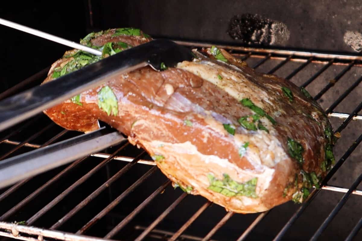 adding marinated tri tip to smoker to be cooked.