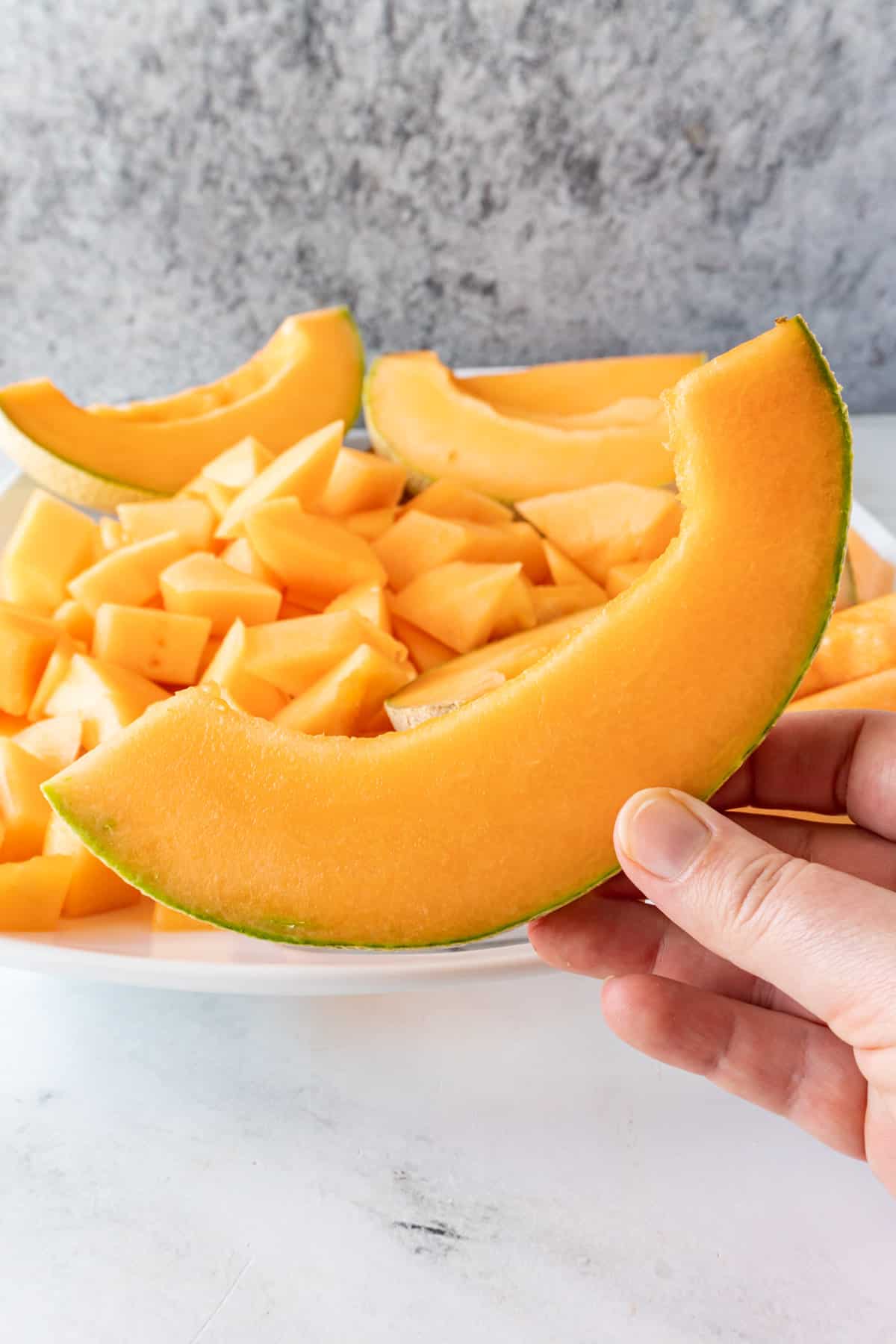 holding a slice of cantaloupe