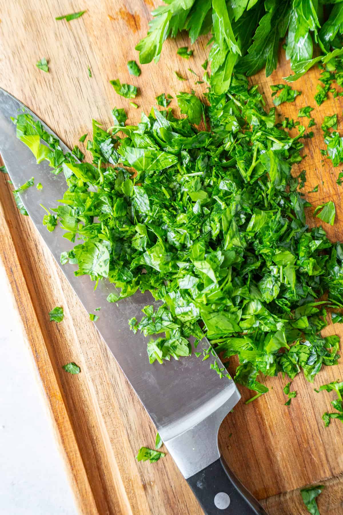 chopped parsley with knife on cutting board.