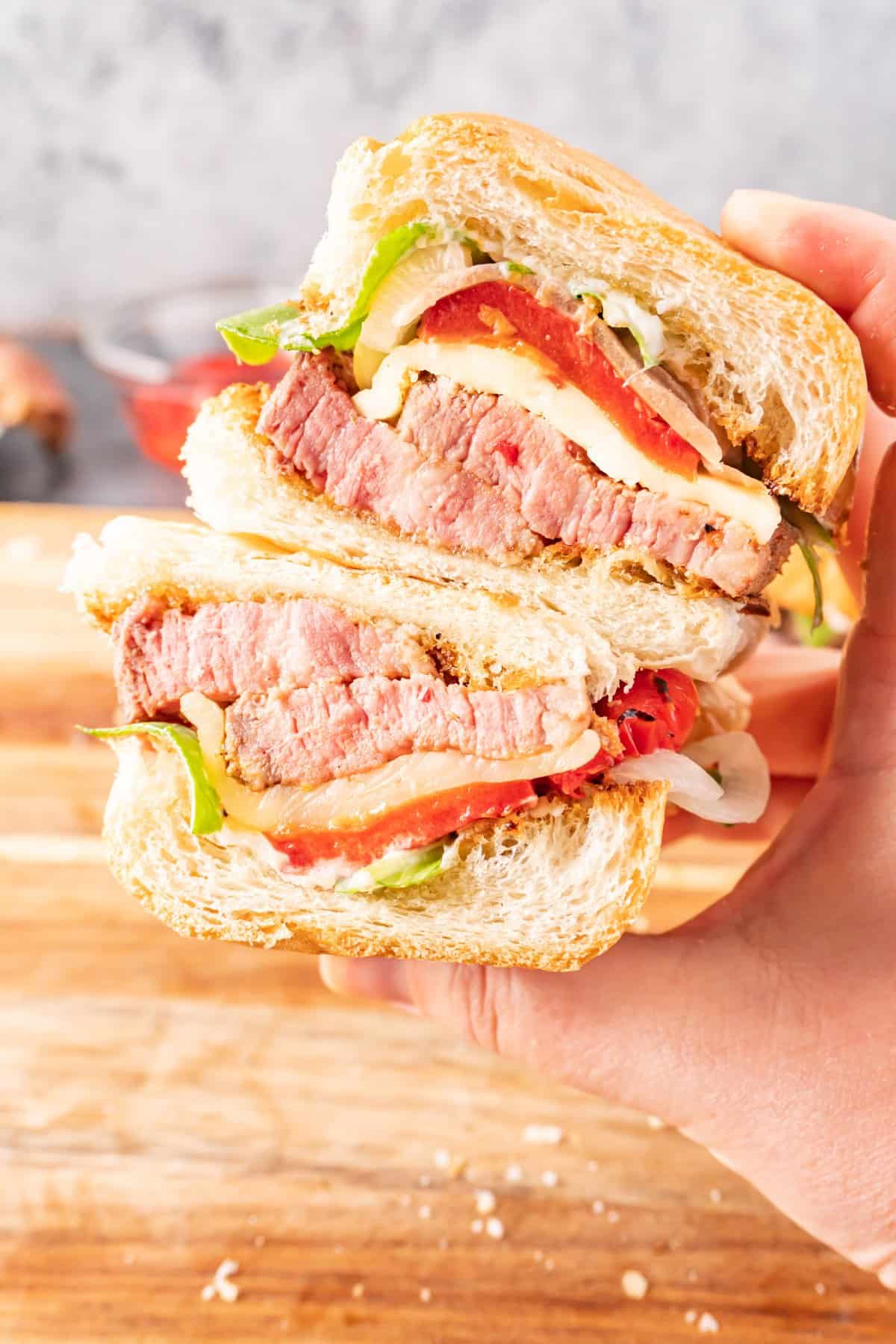 tri tip sandwich being held in had and cut in half.