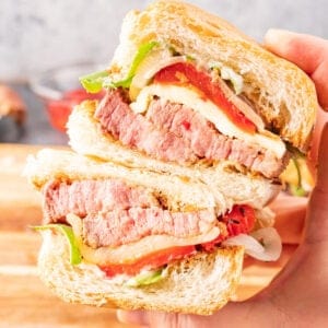 tri tip sandwich being held in had and cut in half featured image.