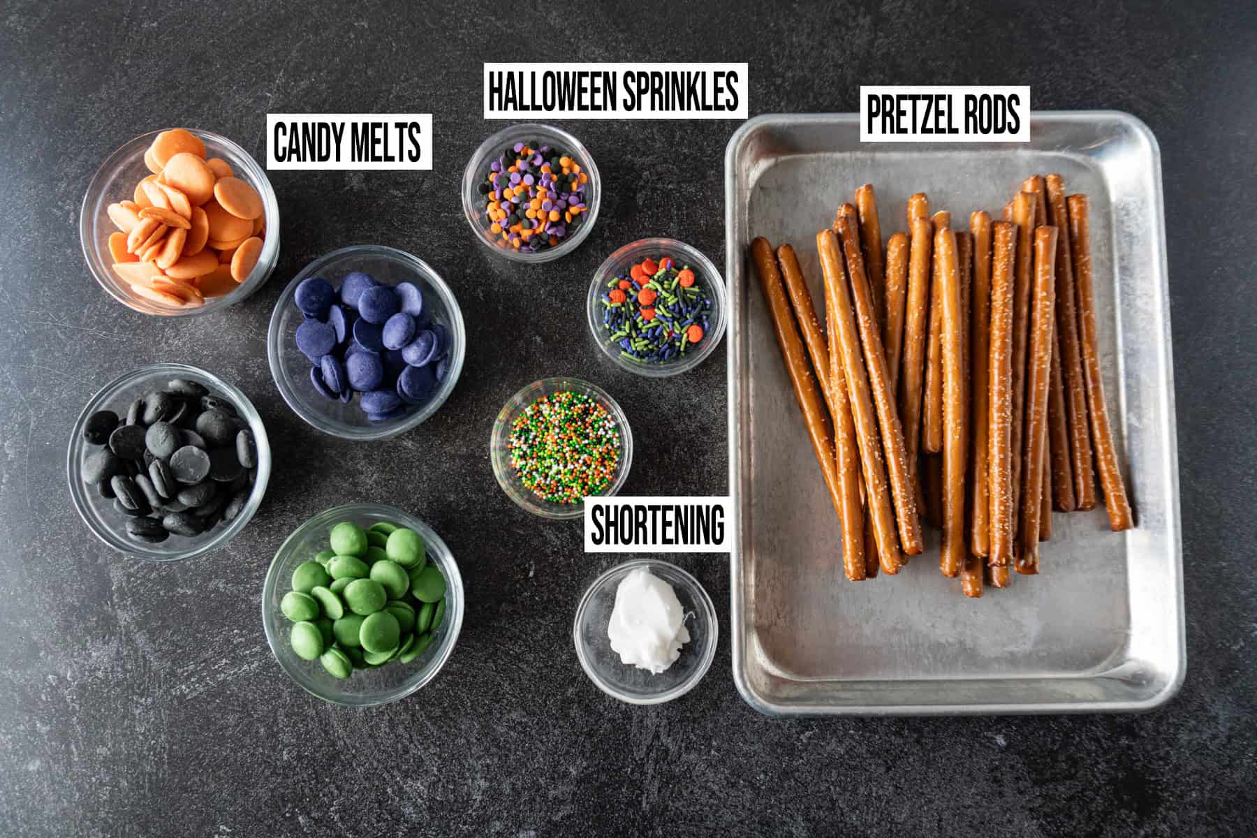 Halloween pretzel rods ingredients in individual bowls and labeled.