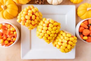 candy corn on the cob on plate with pumpkins and candy around it