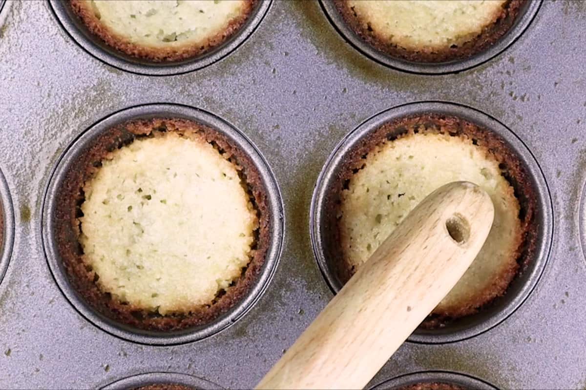 pressing cookie dough down with wooden spoon