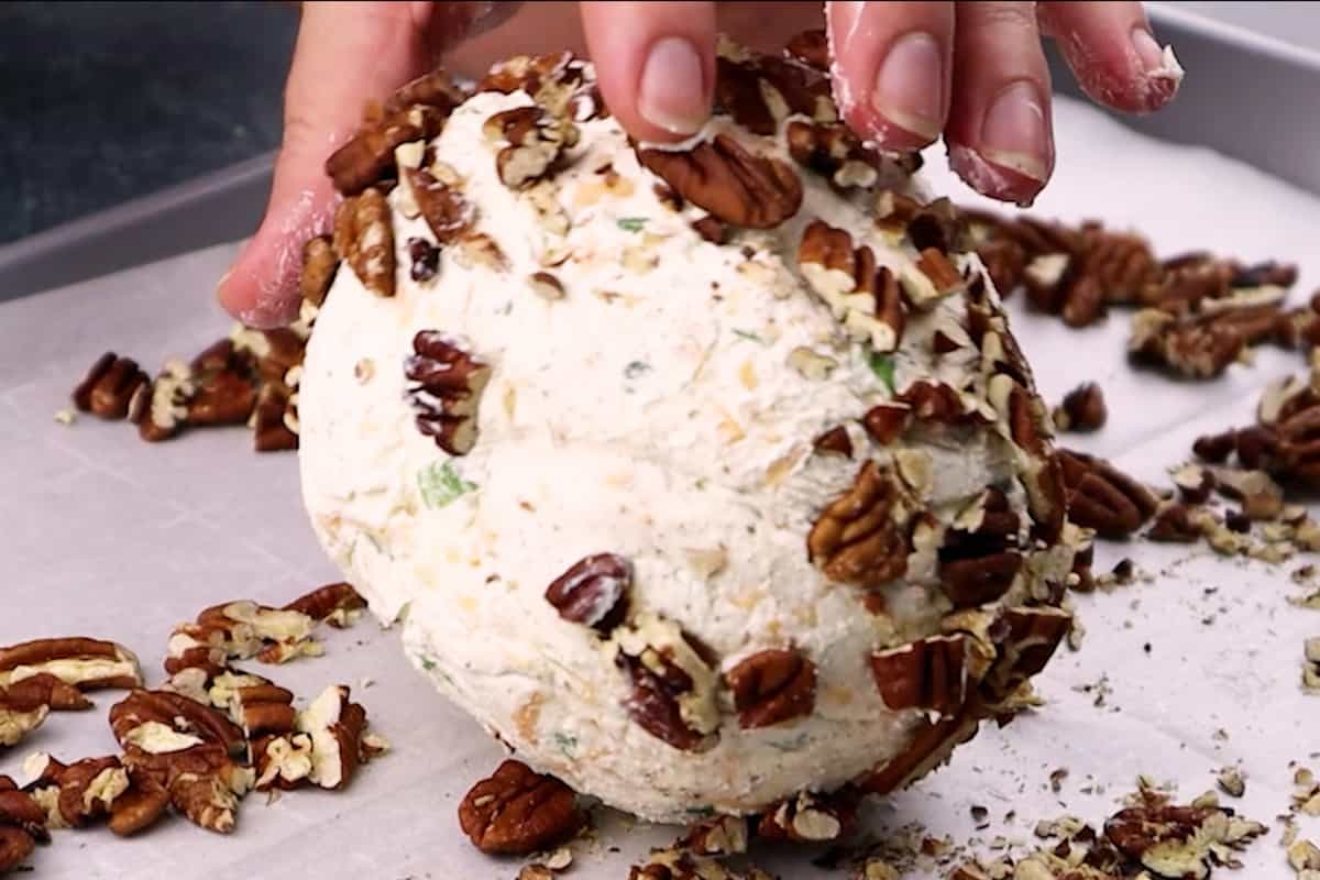 rolling cream cheese ball in pecans