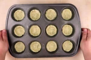 cookie dough pressed in cupcake tin before cooking