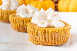 Mini Pumpkin Cheesecakes on plate with whipped cream on top