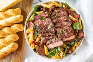 steak pasta next to bread sticks