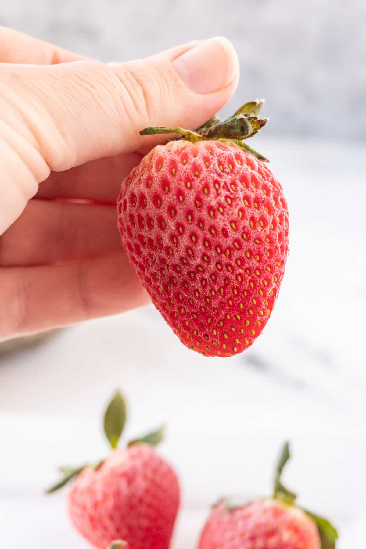 holding a frozen strawberries