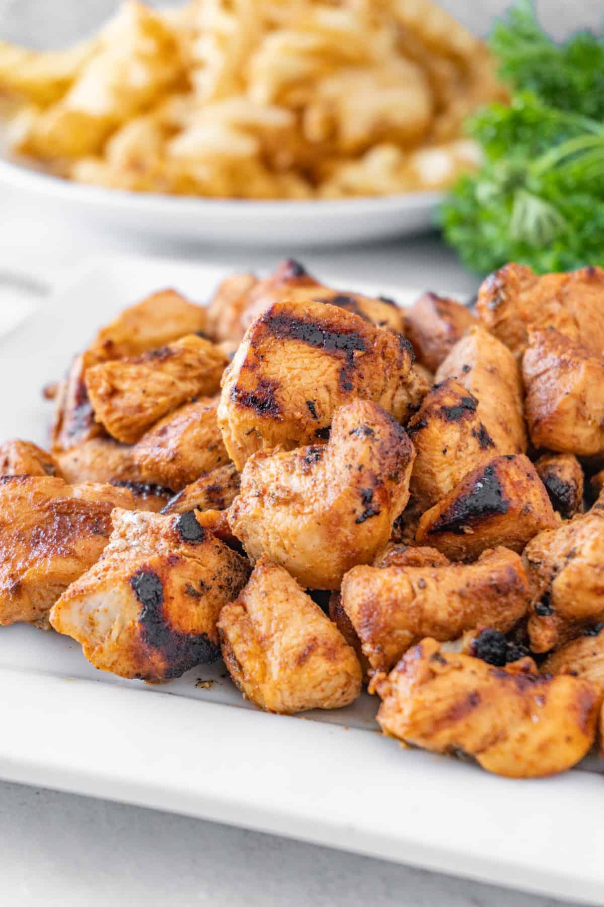 Grilled Chicken Nuggets on plate with fries in background