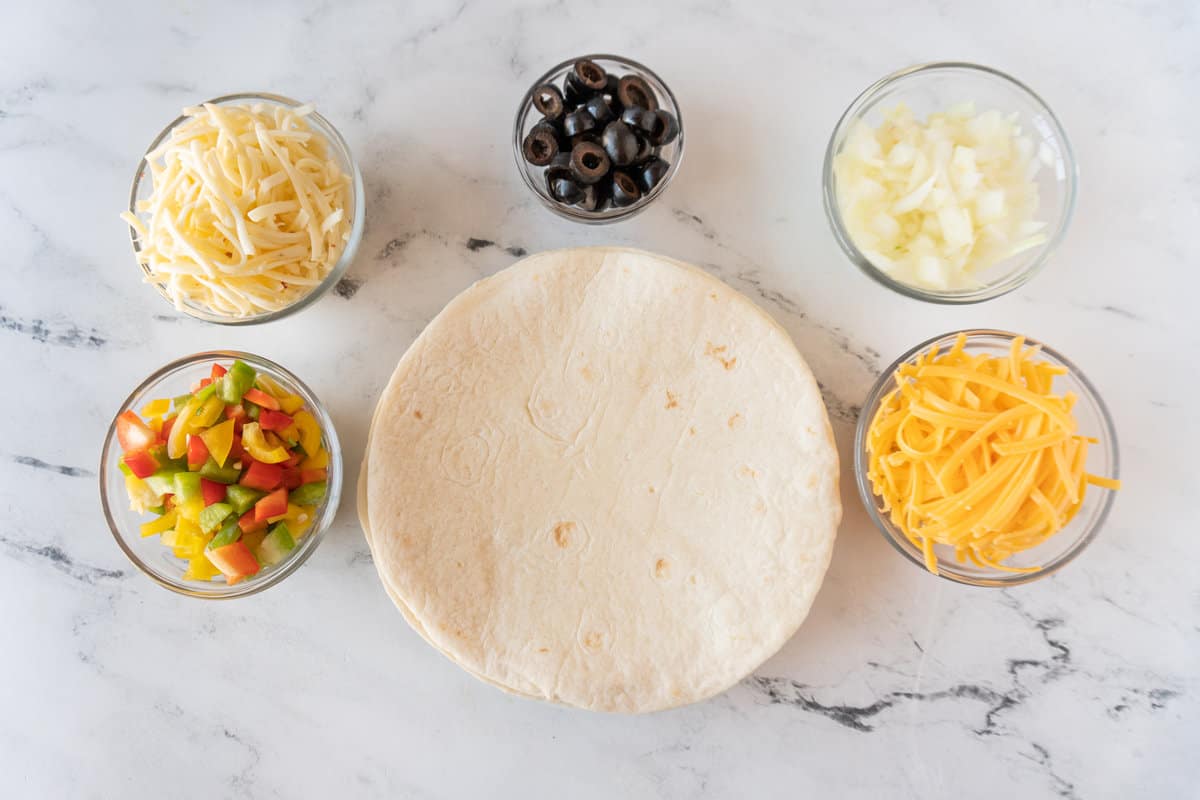 tortilla, cheese, olives, onions, and bell pepper- ingredients laid out