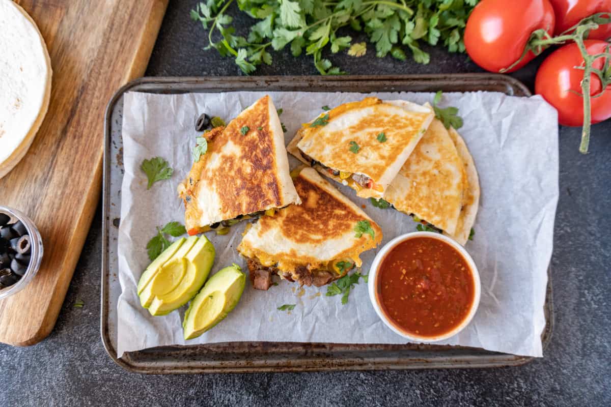 steak quesadilla cut next to salsa and avocado