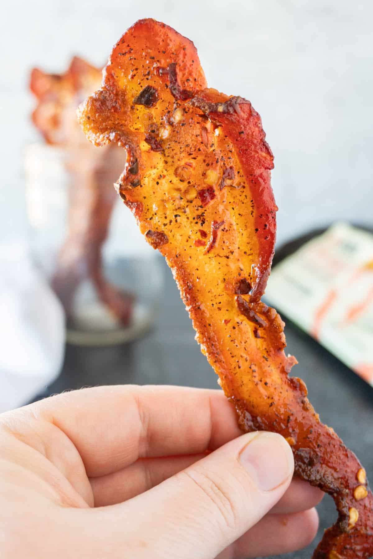 holding a piece of candied bacon