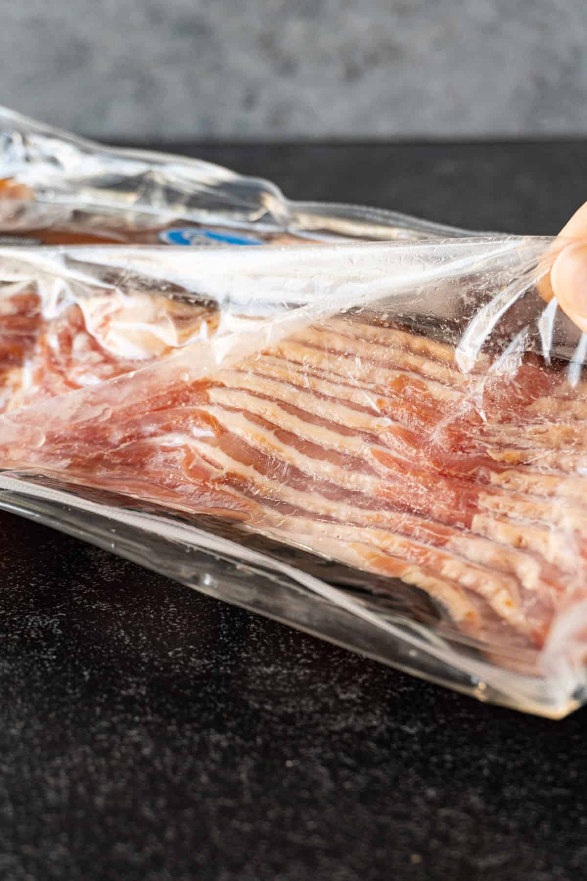 pulling bacon package with bad seal away from bacon to show gap