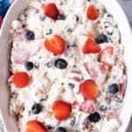red white and blue cheesecake salad in a dish with 4th of July decorations around it