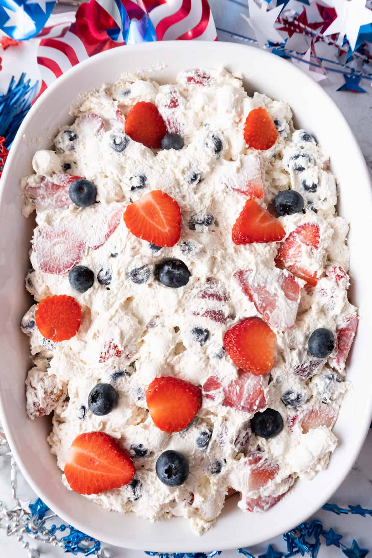 red white and blue cheesecake salad in a dish with 4th of July decorations around it