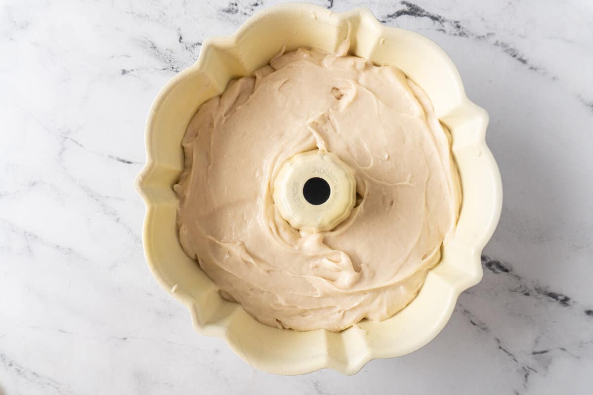 adding white cake batter to bundt pan