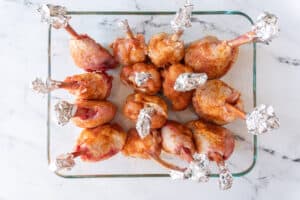 raw chicken lollipops in baking dish top down view