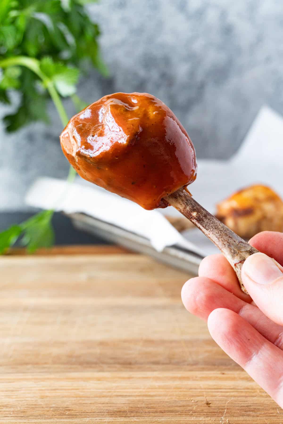 holding a bbq sauce dipped chicken lollipop