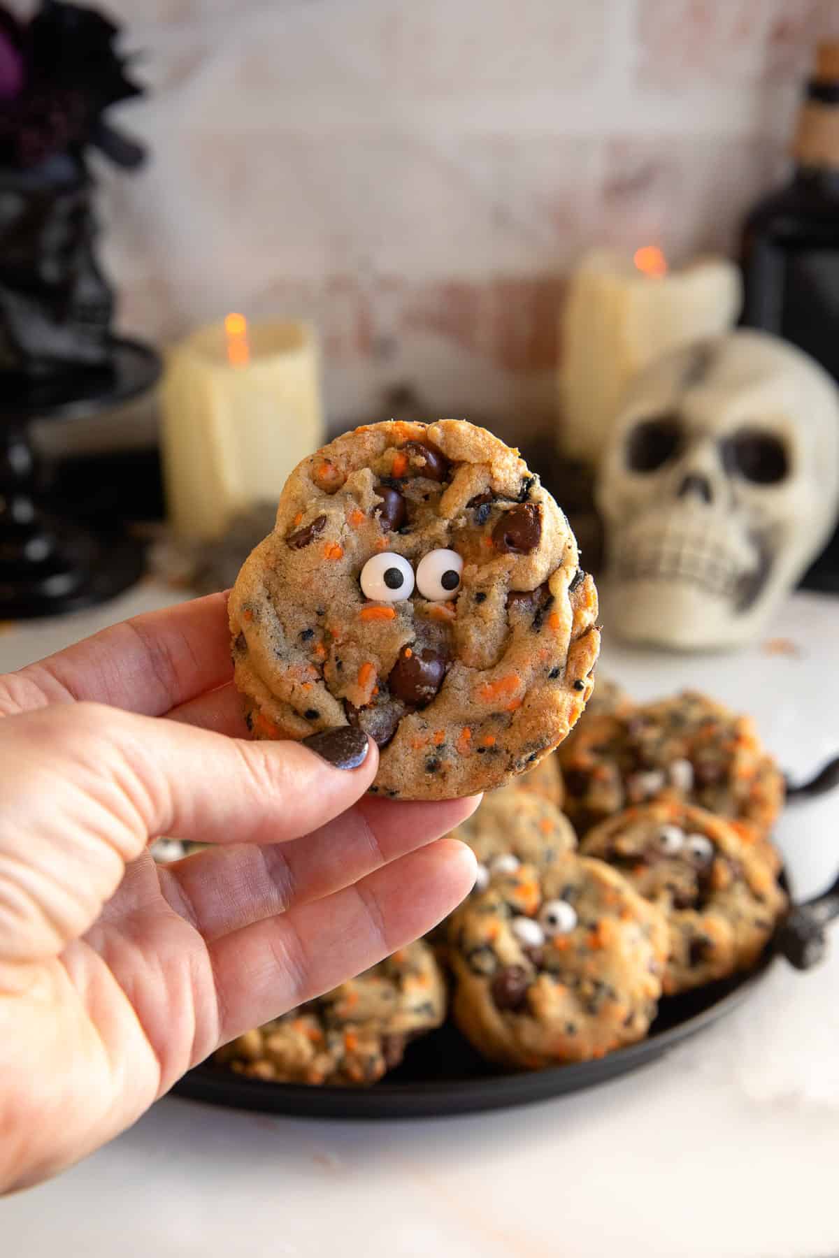 holding a cookie with candy that has eyes