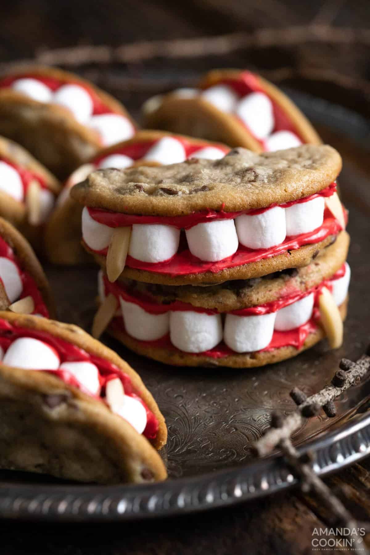 cookies with marshmallows, red frosting, and silvered almonds that looks like vampire mouth