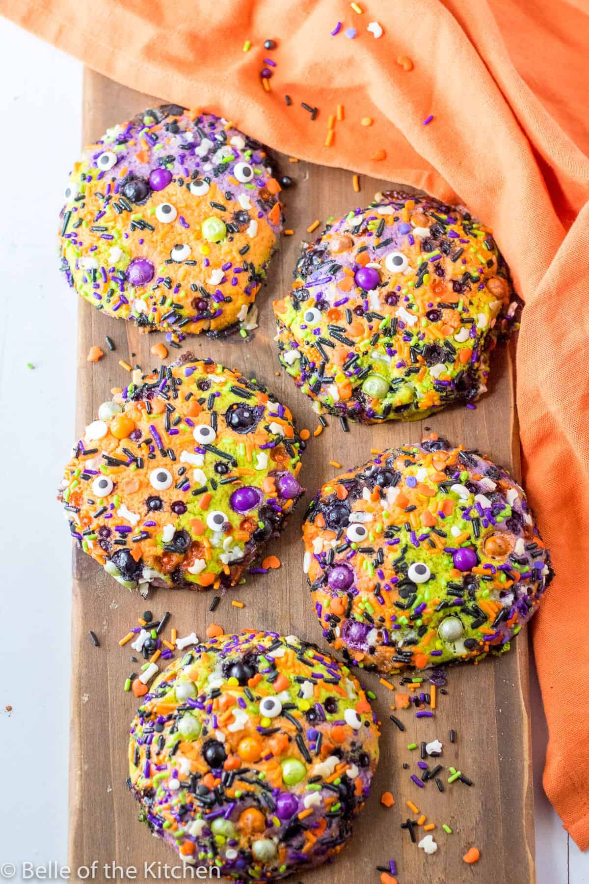 Sugar cookies that are filled sprinkles and are green, orange, and purple