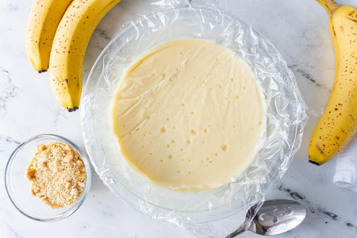 banana pudding in bowl after chilling with plastic wrap over it