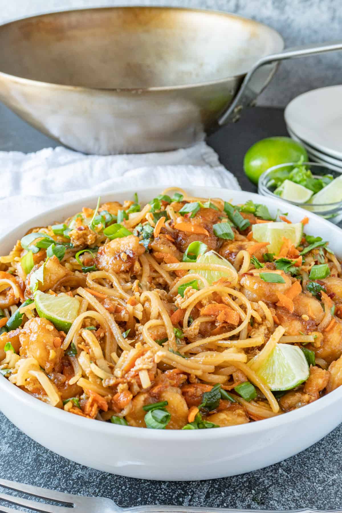 shrimp pad thai in white bowl with wok in background