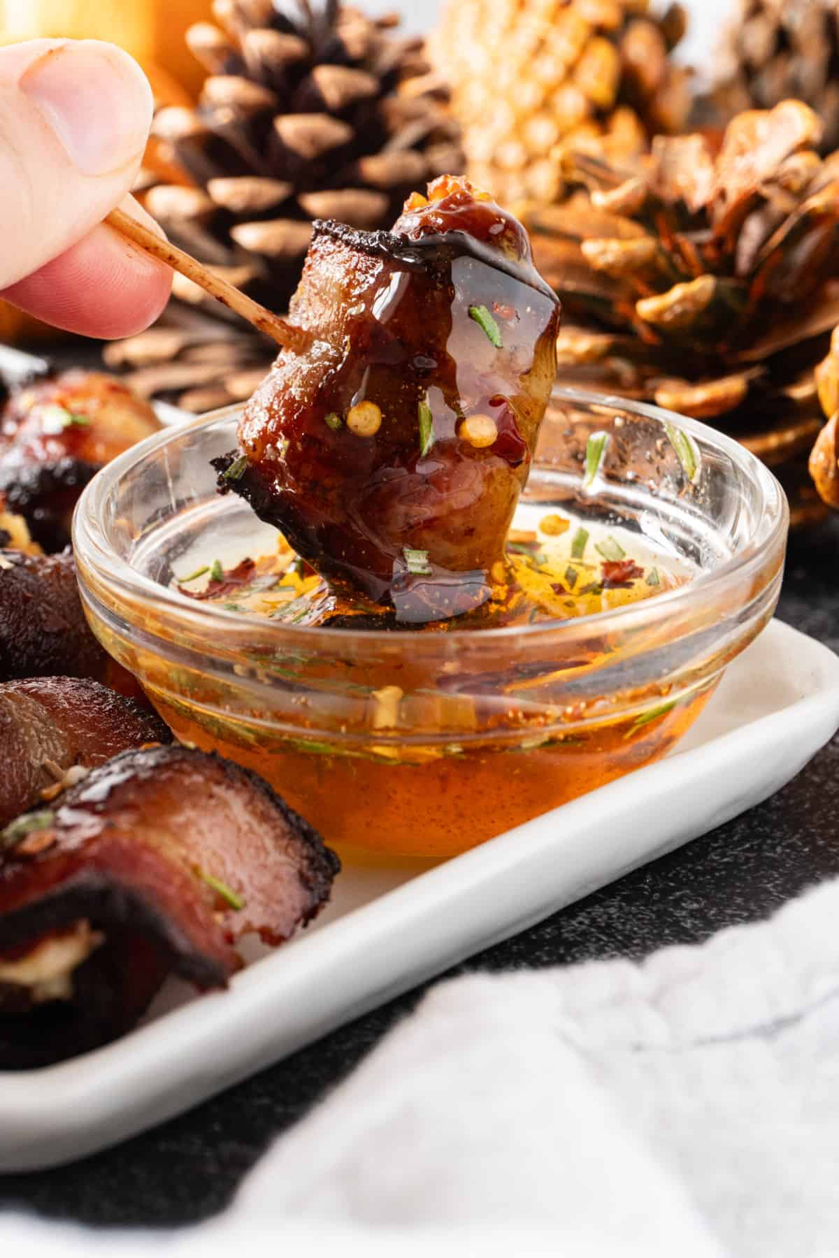 dipping a bacon wrapped date in the glaze