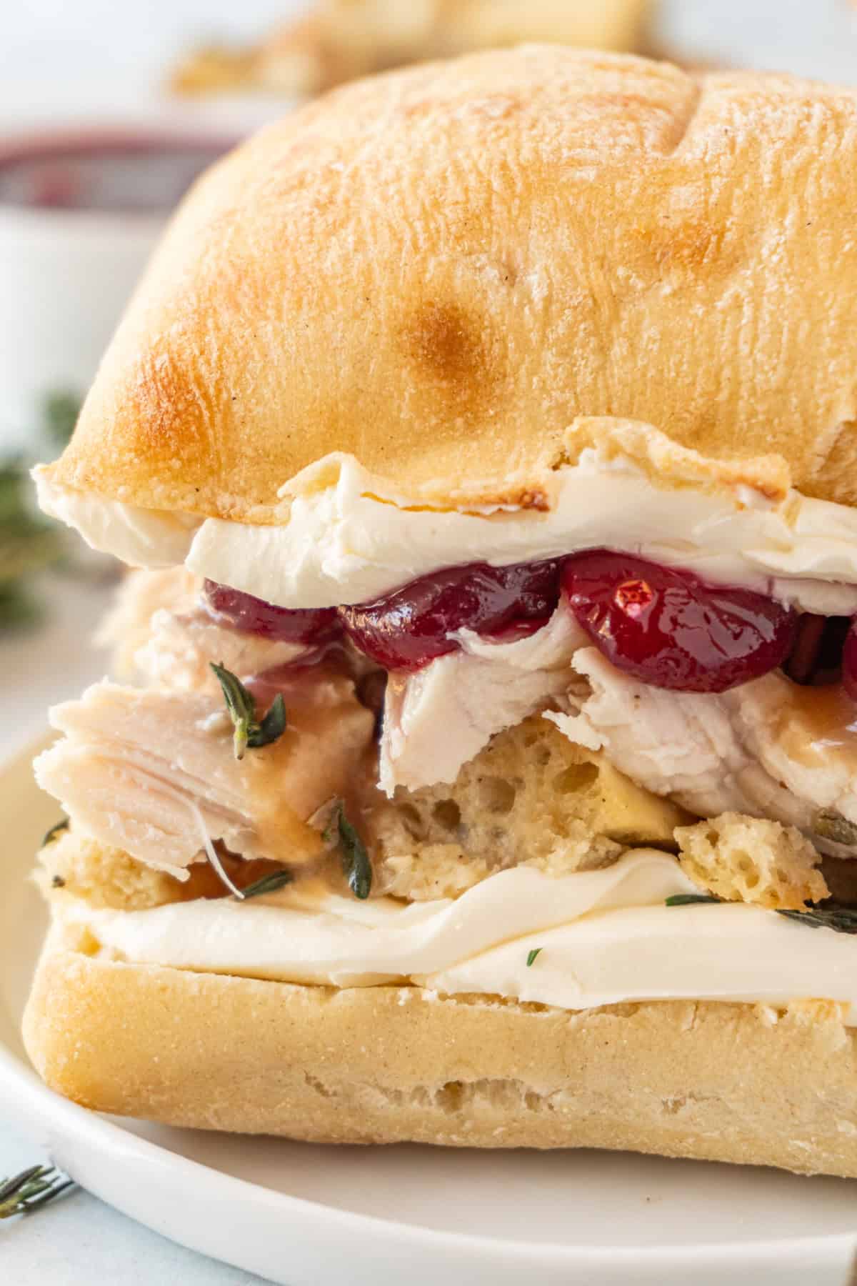 Leftover Thanksgiving Cranberry Sandwich with layers of cream cheese, stuffing, turkey, and cranberry sauce on cibatta.