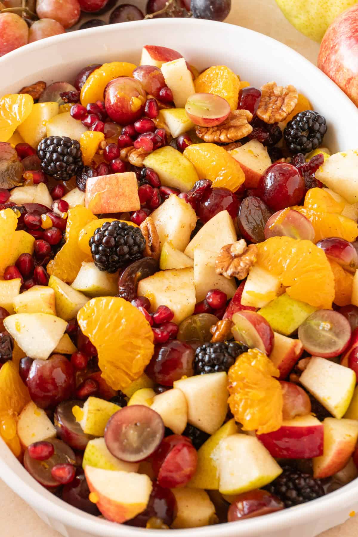 Thanksgiving fruit salad in a white bowl showing vibrant pomegranate seeds, apples, berries, pears, and more!