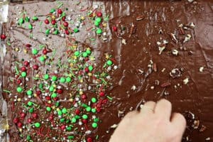 adding sprinkles and nuts to Christmas Cracker Candy