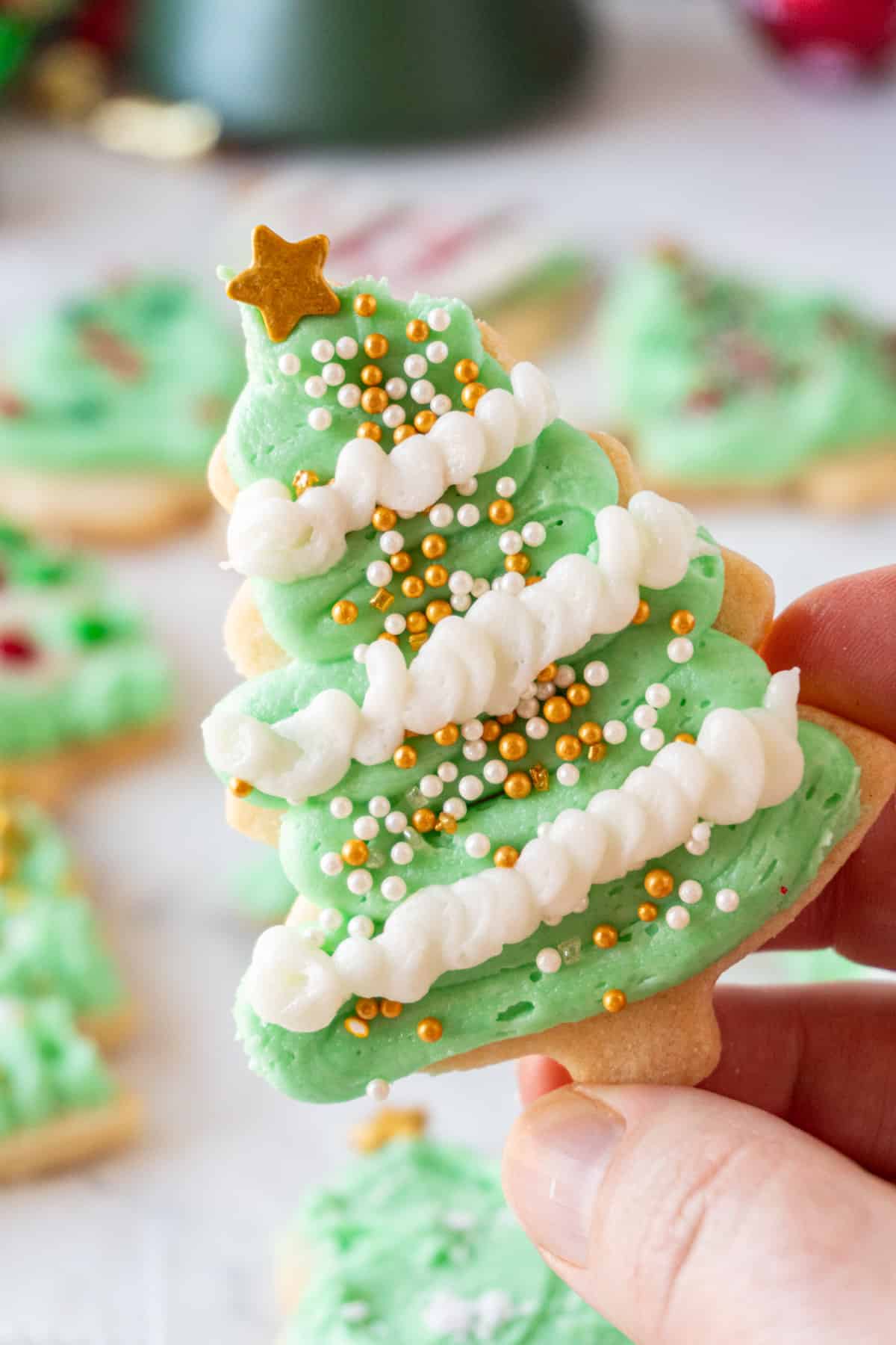 holding Christmas Tree Cookie with green and white frosting