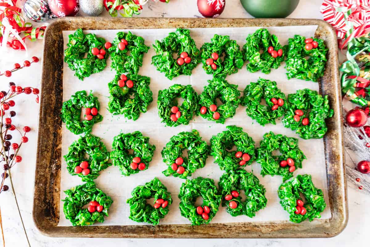 Christmas Wreath Cookies on parchment lined tray surrounded by Christmas decorations.