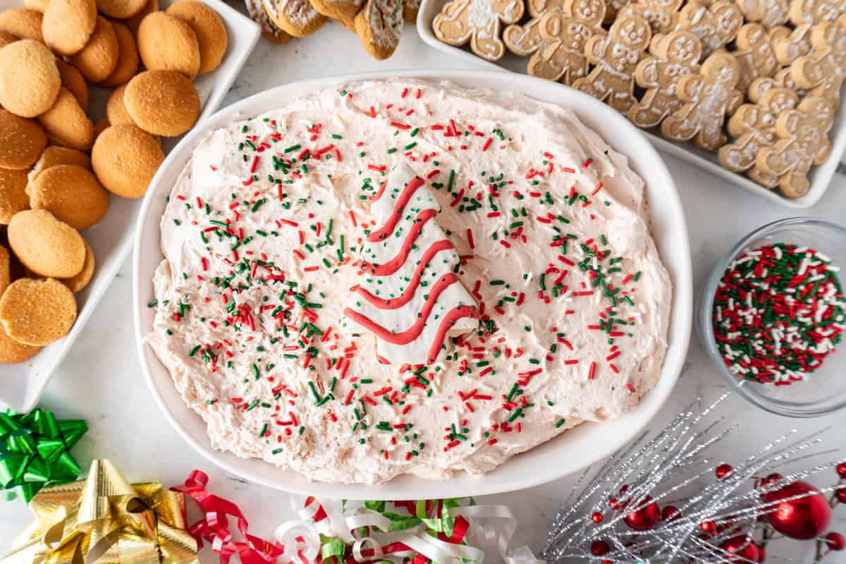 Little Debbie Christmas Tree Dip in white bowl, with extra cake in center of dish, dish is surrounded by cookies to dip into the dip.