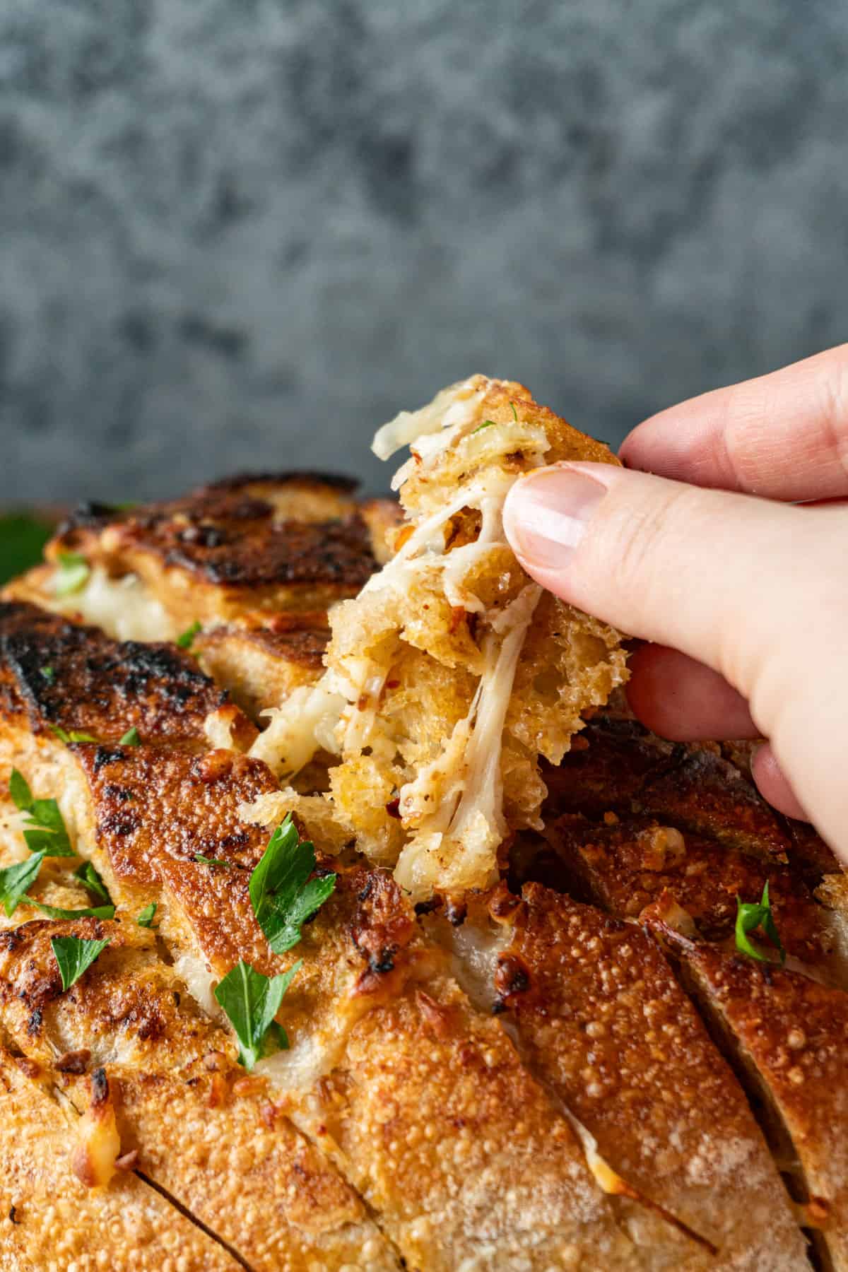 pulling a piece of cheese bread from the loaf