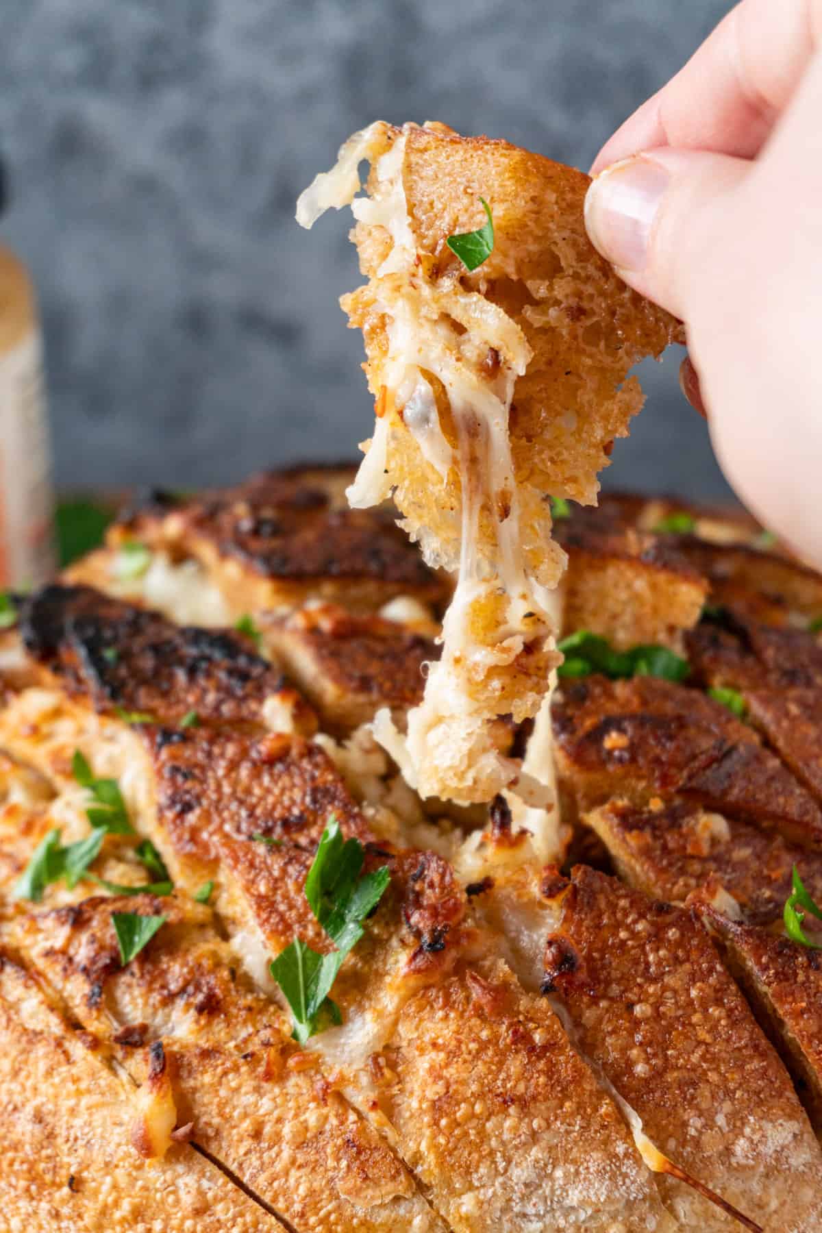 stretchy cheese hanging between loaf and piece held in hand